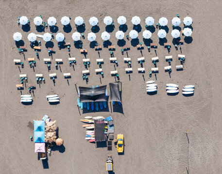 Rows of Umbrellas, tables and surfboards on Beach