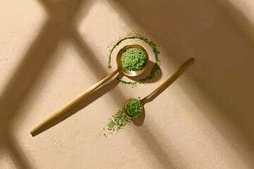 Matcha Tea Powder In Wooden Spoons With Shadows On Beige Surface