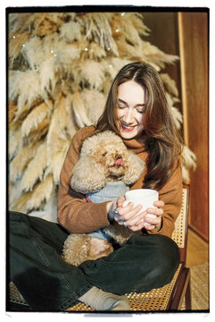 Film photo of a happy woman with cute brown poodle dog and coffee cup