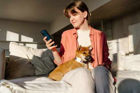 Woman checking smartphone while holding dog with GPS tracker