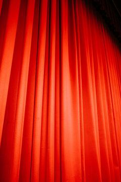 Red stage curtain hanging in a theater, creating a dramatic atmosphere
