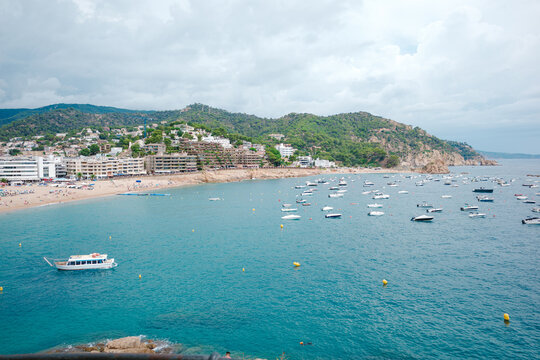 Boats floating near tossa de mar beach on cloudy day