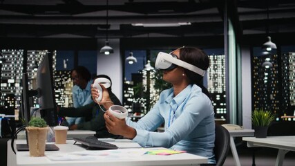 African american woman employs AI gadget with virtual reality in dark office, doing overtime at the corporation workspace with VR glasses to ensure fact checking and analyze projections. Camera A. - Powered by Adobe