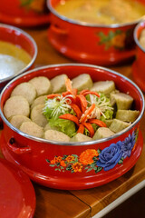 Indonesian lontong (rice cakes) neatly arranged in a red enamel tiffin tray with lettuce and carved chili garnish. ideal for culinary, cultural and menu use
