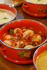 Indonesian boiled eggs cooked in spicy red chili sauce and served in a white enamel bowl with floral motif. Authentic Indonesian home cooking ideal for culinary and cultural editorials
