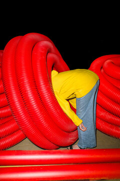 Curious Person with Head Inside Red Tubes