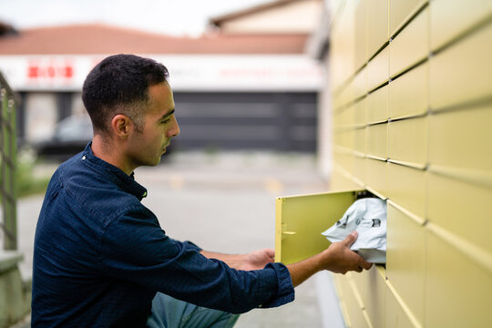 Young adult retrieves package from parcel locker, mailbox