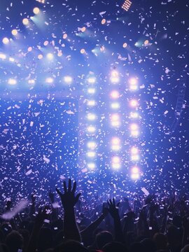Crowd celebrating beneath lights and heavy confetti