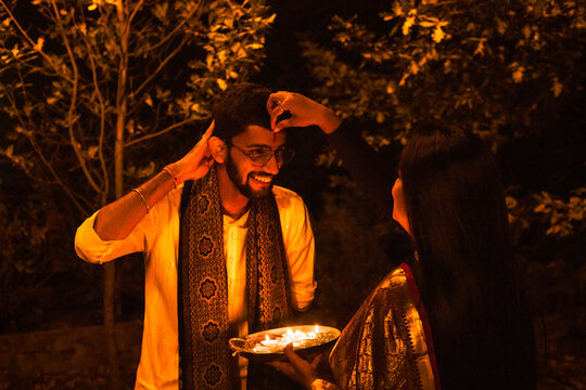 Indian woman making Tilaka for man on Diwali.