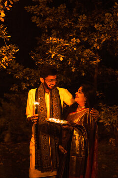 Indian man and woman with sparkles celebrating Diwali night.