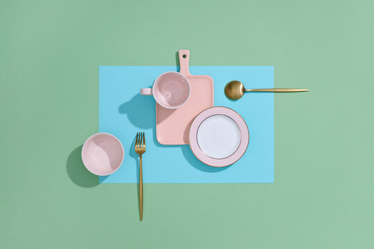 Elegant tableware is displayed on a backdrop of blue and green.