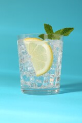Refreshing water with lemon, mint and ice on light blue background