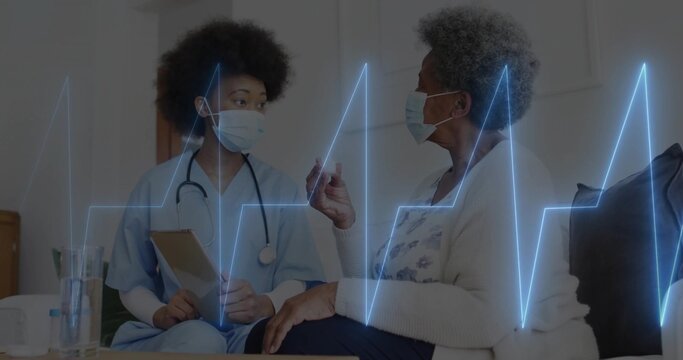 Sitting masked nurse with stethoscope holding clipboard beside patient at home showing ECG line
