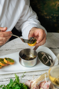 Chef serving escargot on garlic herb bread with tongs