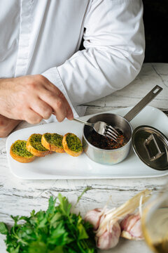  Chef preparing garlic herb bread with sauce in small pan