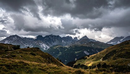 Fototapeta premium Dramatic Mountain Range Landscape with Stormy Sky and Grassy Hills in Sunlight