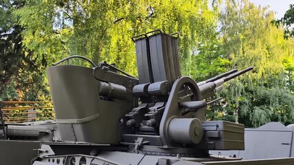 A detailed closeup view of an antiaircraft gun prominently displayed in the great outdoors amid lush greenery
