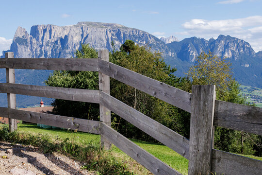 Mountain landscape with green pasture behind a wooden fence