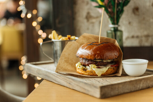 Gourmet burger with fries served on wooden tray