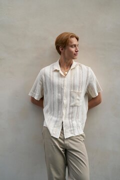 Young Man Posing Casually Against a Light Wall in Soft Attire