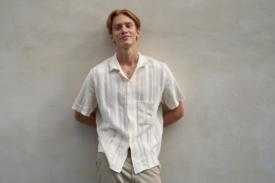 Young Man Poses Casually Against a Textured Wall in Sunlight