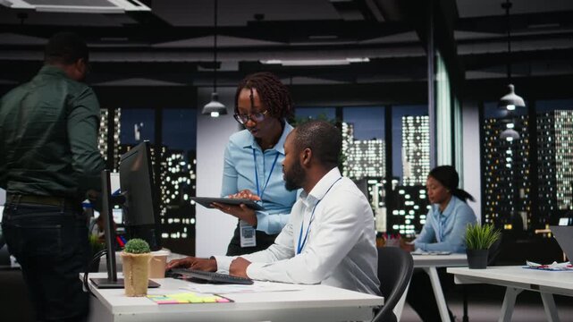 Black company advisors doing teamwork at night to meet deadlines, completing monthly reports and KPI numbers for business productivity. Tasks in strategy room after hours. Camera A.
