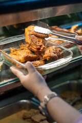 Hands Serving Fried Chicken from Food Display in Indonesian Restaurant