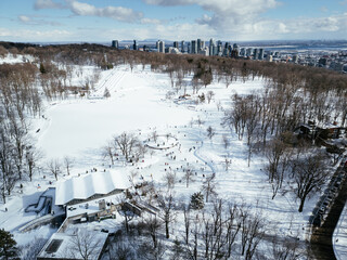 Winter aerial view of Montreal skyline with snowy Mount Royal Park and frozen Beaver Lake. g.