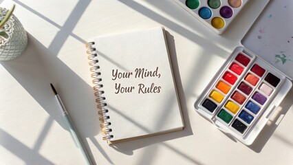 Inspirational Notebook with Watercolor Palette on Table Surrounded by Sunlight and Shadow Patterns