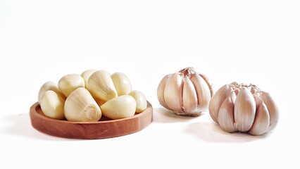 Garlic cloves and garlic bulb in a wooden plate. Isolated on white background with copy space. Clipping Path. Perfect for design element, food recipe or any commercial usage. Front view.