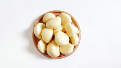 Garlic cloves in a wooden plate. Isolated on white background with copy space. Clipping Path. Perfect for design element, food recipe or any commercial usage. Top view. Flat lay.