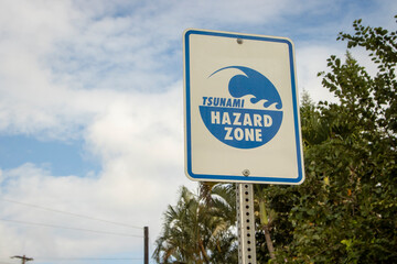 A sign warning of a Tsunami Hazard Zone against a blue sky