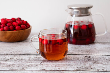 Hawthorn tea in a glass teapot and a cup on the table. Vitamin health drink.