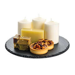Arrangement of candles, soap, and pastries on a dark stone plate