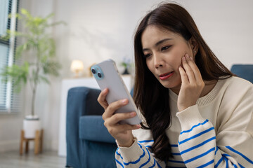 A young woman sits on the floor with a cushion, smiling happily while using her smartphone. She appears relaxed and joyful, enjoying leisure time at home with positive energy.
