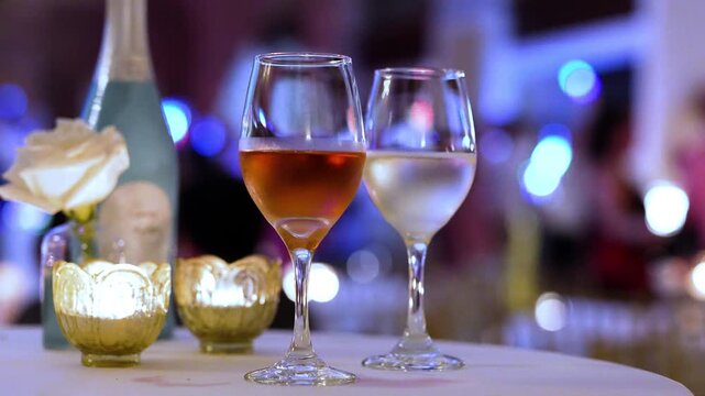 Wine on a table during a wedding reception or party with people dancing and having fun in the background. 