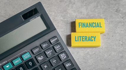 Financial Literacy Text on Yellow Blocks Next to Calculator for Business and Education