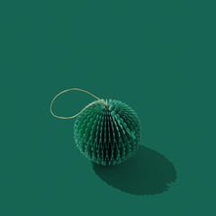 Green Paper Christmas Ornaments as Christmas round ball, winter seasonal holiday decorations on green with copy space, Happy holidays background. Closeup side view diy bauble, xmas monochrome card