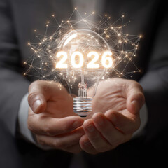 Businessman holding light bulb with 2026 target, symbolizing vision and innovation for future goals