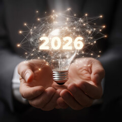Businessman holding light bulb with 2026 target, symbolizing vision and innovation for future goals