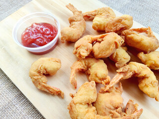 Golden Brown Crispy Fried Shrimp Arranged on a Wooden Platter with Red Dipping Sauce