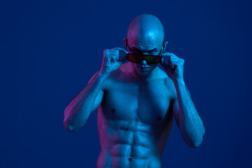 A striking image of a man with a bold expression, showcasing his confidence and strength against a blue backdrop, highlighting fitness and determination.