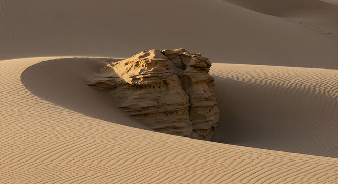 Monumental rock formation amidst rolling sand dunes in the vast desert landscape - Powered by Adobe
