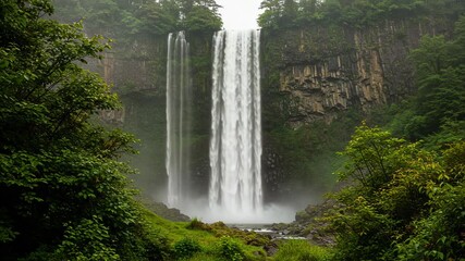 Majestic waterfall cascades down a lush green cliff face surrounded by trees