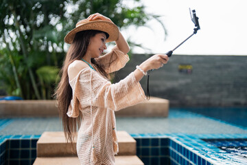 Young Hispanic Gen Z Woman in Swimwear Creating Travel Vlog as Influencer by Resort Pool in Summer