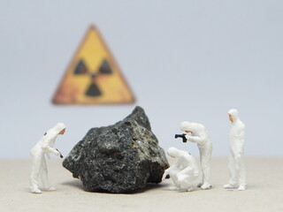 Mini toy of action figure at table with blur background. Miniature photography concept design. Minifigure of worker character wearing hazmat suit with uranium stone and radioactive symbol. © awstoys
