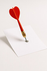 Red Dart Piercing White Paper on Beige Background