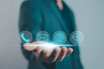 Businessman holding digital contact icons, including phone, email, and chat symbols. Modern communication concept for customer service, marketing, and business technology design.