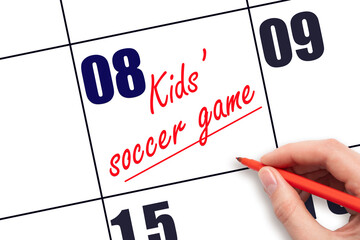 8 th day of the month. Hand writing Kids' soccer game reminder and drawing a line on calendar....