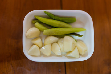 Green chili and peel garlic on white bowl